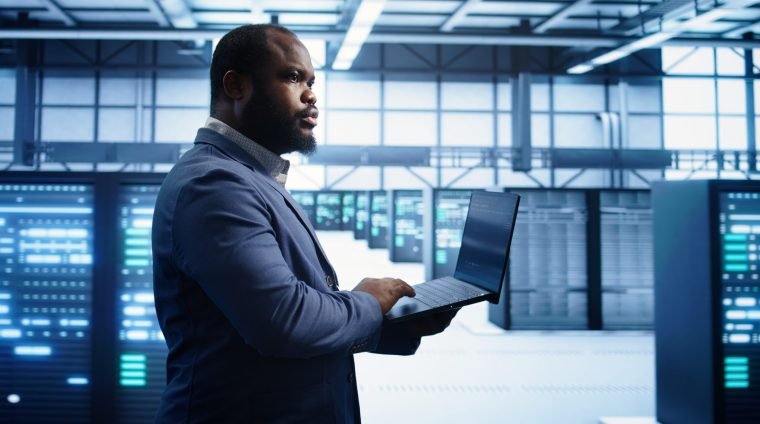 Technician in data center workspace running system diagnostic tests and error checking utilities to fix issues. Employee looks for network issues affecting rigs performance and connectivity, camera B