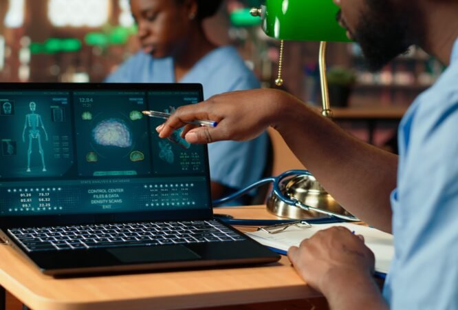 Black med school scholar studying and taking notes using online information, reviews a thesis project in the library. Young man collecting academic data for medical research. Camera B.