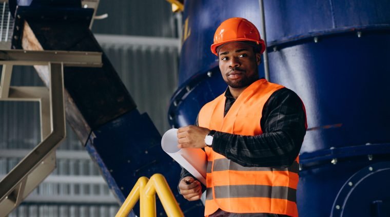 African american worker standing in uniform wearing a safety hat in a factory