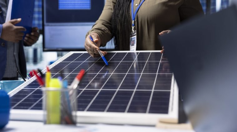 Shareholders meet with industrial plant manager to review solar panel components, analyzing material quality. Photovoltaics factory management executive presents solar panel features to investors